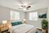 Bright and cozy bedroom with modern decor, featuring a comfortable bed, stylish lamps, and serene nature artwork, complemented by natural light from large windows.
