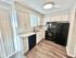Modern kitchen with sleek black appliances, spacious white cabinetry, and elegant wood flooring.