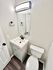 Modern bathroom featuring a sleek vanity with a raised sink, minimalist mirror, and elegant light fixture.