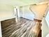 Inviting living space with elegant wood flooring and natural light, leading to a modern kitchen and staircase.