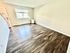 Bright and inviting living room with large windows and elegant dark wood flooring, creating a spacious ambiance.