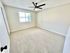 Bright and airy bedroom with large window, soft carpet flooring, and modern ceiling fan.