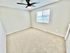 Bright and spacious bedroom with plush carpeting and modern ceiling fan, featuring a large window with natural light.