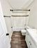 Modern bathroom with elegant tile accents, sleek white vanity, and wood-style flooring.