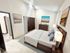 Inviting bedroom with elegant wooden furniture, cozy bed with plush pillows, and serene artwork, perfect for relaxation.