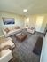 Inviting living room with plush carpeting, elegant beige seating, and modern decor, perfect for relaxation and entertainment.