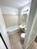 Modern bathroom with gleaming white fixtures, a sleek bathtub, overhead lighting, and elegant tile flooring.
