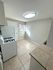 Bright kitchen with large tiles, modern light fixture, and natural light flowing through a window, creating an inviting cooking space.