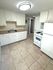 Bright and spacious kitchen with modern white cabinetry, tile flooring, and sleek appliances, perfect for culinary creativity.