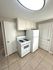Bright kitchen with modern appliances, featuring a sleek white stove, refrigerator, and ample cabinet space on elegant tiled flooring.