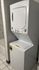 Modern apartment bathroom featuring an efficient stackable washer and dryer unit adjacent to a sleek shower area.
