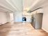 Modern open-concept apartment featuring a spacious kitchen with stainless steel appliances and sleek hardwood floors.
