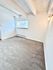 Bright and inviting room with plush carpet, large window, and elegant exposed beams.