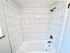 Modern bathroom with sleek white tiles and a stainless steel shower fixture.