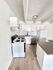 Modern kitchen with sleek white cabinetry, stainless steel appliances, and elegant countertops, complemented by light wood flooring.