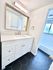 Bright and modern bathroom featuring sleek black hexagonal tiles, a stylish white vanity with ample storage, and a spacious bathtub area.