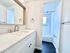 Contemporary bathroom with sleek vanity, elegant fixtures, and inviting bathtub under natural light.