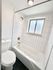 Bright, modern bathroom featuring sleek white tiles, a pristine bathtub, and contemporary fixtures.