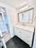 Modern bathroom featuring a sleek white vanity with ample storage, large mirror, and elegant black hexagon floor tiles.