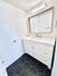 Modern bathroom with sleek white vanity, large mirror, and stylish hexagonal black tiles.