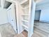 Contemporary apartment interior featuring a bright hallway with built-in shelves, carpeted and laminate flooring, and double-door closet.