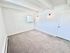 Bright and inviting empty room with plush carpet, white walls, and natural light from a small window. Elegant wall sconces add a modern touch.
