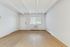 Bright and spacious living room with elegant wooden flooring, large window, and minimalistic white walls.