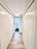 Bright hallway with elegant wood flooring leading to a modern bathroom with hexagonal tiles.