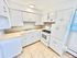 Bright and inviting kitchen with ample white cabinetry, modern stove, and elegant tile flooring.