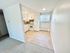 Bright, compact kitchen with white cabinets and tiled flooring, seamlessly connected to the cozy living area with plush carpeting.