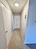 Inviting hallway with soft carpet flooring and modern ceiling light, leading to a spacious storage cabinet.