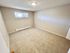 Bright and spacious bedroom featuring soft carpet flooring, neutral walls, and ample natural light from a large window, perfect for comfort and relaxation.