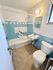 Charming bathroom with retro blue tiles, a pristine bathtub, and modern amenities. Bright and inviting space with natural light.