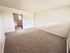 Bright, carpeted room leading to a hallway with natural light and a cozy atmosphere.
