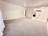 Bright and inviting living room with plush carpeting, seamlessly connecting to a cozy kitchen area.
