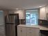 Modern kitchen with sleek stainless steel appliances, white cabinetry, and natural light streaming through patio doors.