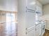 Bright, open-concept apartment featuring a modern kitchen with white cabinetry and a spacious living area with large patio doors inviting natural light.