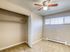 Bright and cozy bedroom with beige walls, modern ceiling fan, large window, and spacious built-in closet.