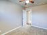 Bright and cozy bedroom with plush carpet and ceiling fan, leading to a welcoming hallway.