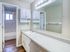 Bright and modern bathroom with sleek vanity, large mirror, and luxurious bathtub, featuring elegant lighting and contemporary cabinetry.