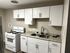Modern kitchen with sleek white cabinets, granite countertops, and a four-burner stove offering a contemporary cooking space.