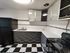 Chic kitchen with modern black and white checkered flooring, sleek cabinetry, and glossy appliances, perfect for culinary enthusiasts.