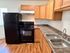 Charming kitchen with sleek black appliances, double sink, and warm oak cabinetry, complemented by elegant wood flooring.