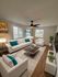 Inviting living room with modern furnishings, featuring plush white sofas, vibrant teal accents, and sleek wooden coffee table on a cozy area rug, ideal for relaxing.