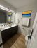 Modern bathroom with dual sink vanity, sleek fixtures, and vibrant artwork, featuring elegant lighting and warm wood flooring.