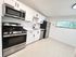 Modern kitchen with sleek stainless steel appliances, elegant white cabinetry, and large window offering natural light.