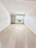 Bright, airy room with clean white walls, elegant wood flooring, and natural lighting from a window with a cozy air conditioning unit.