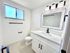 Modern bathroom with sleek vanity, large mirror, and elegant lighting fixtures.