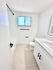 Bright and modern bathroom with white cabinetry, sleek countertops, and elegant fixtures. Features a classic bathtub and large window for natural light.