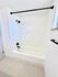 Modern bathroom featuring a sleek white bathtub with black fixtures and elegant tile design.